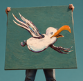 Mand holder mågemaleri mod teal himmel